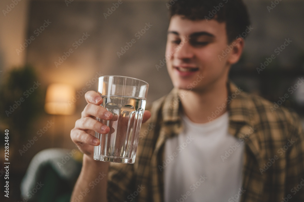 man young caucasian male teenager hold glass of water at home man young caucasian male teenager hold glass of water at home