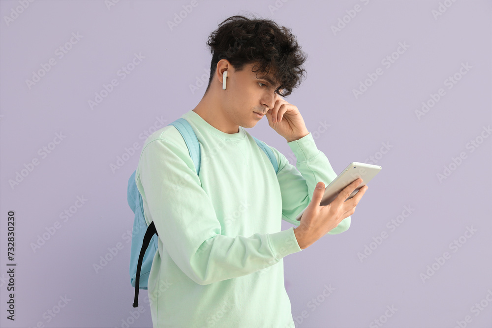 Male student with tablet computer on lilac background Male student with tablet computer on lilac background