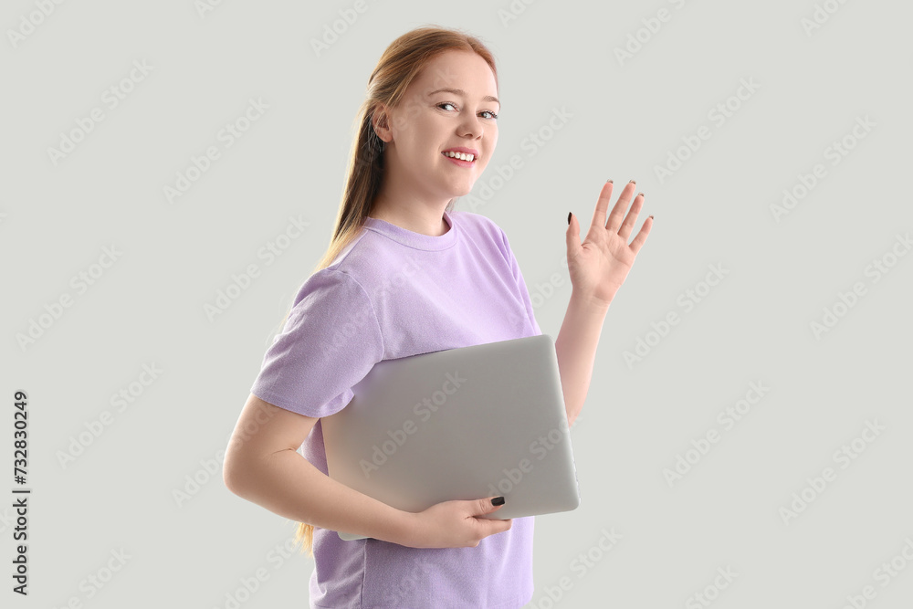 Female programmer with laptop waving hand on light background Female programmer with laptop waving hand on light background