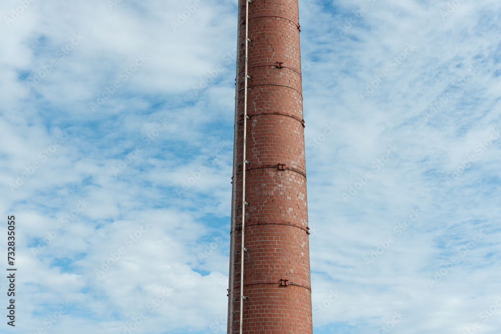 old factory chimney or smokestack on a blue sky with clouds