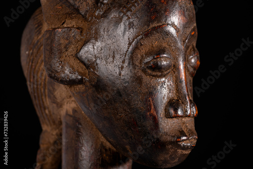 Close-up of an African female figure carved in wood isolated on black. Traditional African art with balanced shapes and volumes and a beautiful dark brown patina. photo
