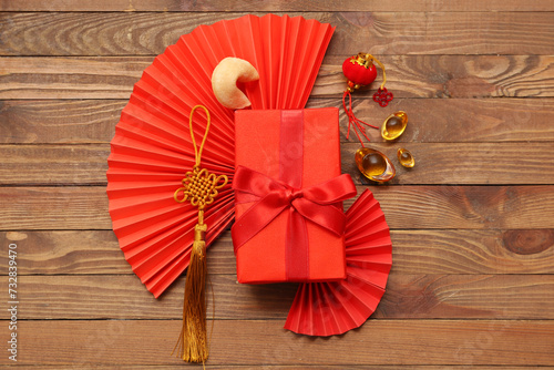 Gift box with fortune cookie and Chinese symbols on wooden background. New Year celebration