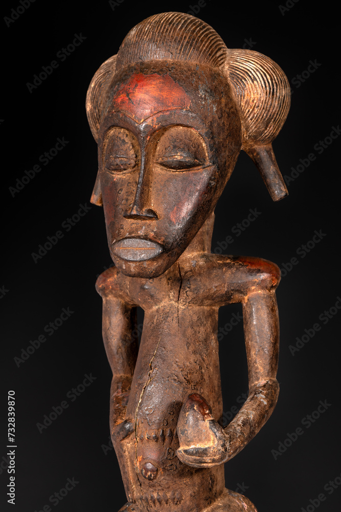 Close-up of a wooden Senufo Male figure from Ivory Coast with a brown patina isolated on black. Tribal African art, showcasing masterful craftsmanship and spiritual symbolism.