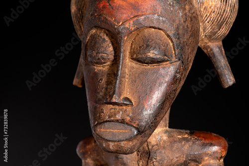 Close-up of a wooden Senufo Male figure from Ivory Coast with a brown patina isolated on black. Tribal African art, showcasing masterful craftsmanship and spiritual symbolism.