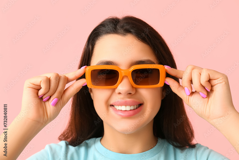 Young happy smiling woman in sunglasses on pink background, closeup Young happy smiling woman in sunglasses on pink background, closeup