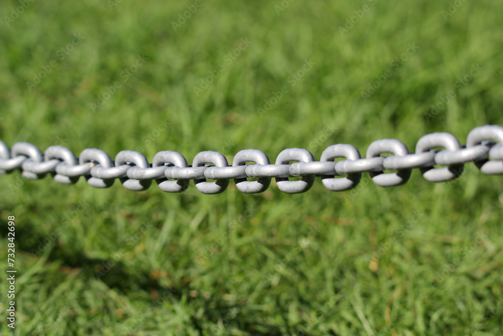 Links on a metal chain against a green grass background Links on a metal chain against a green grass background