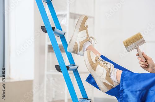 Fotografie Female painter with brush falling down from stepladder in room, closeup