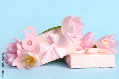Figure 8 made of paper with gift boxes and beautiful pink tulips on blue background. International Women s Day