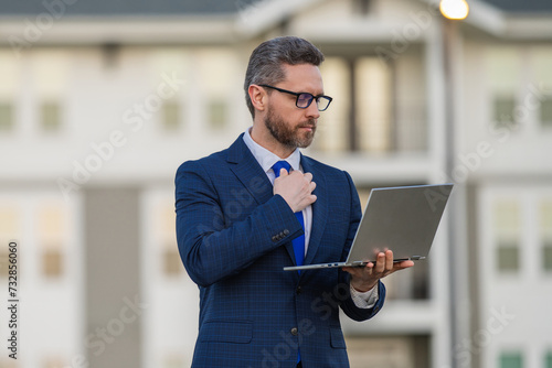 Serious hispanic man working on laptop. Businessman checking email on laptop, writing message in social network, using internet, searching information on laptops. Business man using laptop. photo