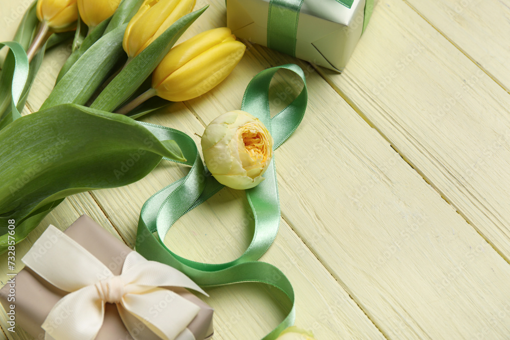 Composition with figure 8 made of ribbon, flowers and gift boxes on yellow wooden background. International Women's Day celebration Composition with figure 8 made of ribbon, flowers and gift boxes on yellow wooden background. International Women's Day celebration