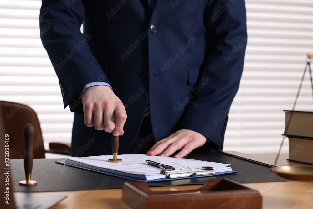 Notary stamping document at table in office, closeup Notary stamping document at table in office, closeup