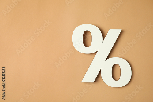 White percent sign on light brown background, top view. Space for text