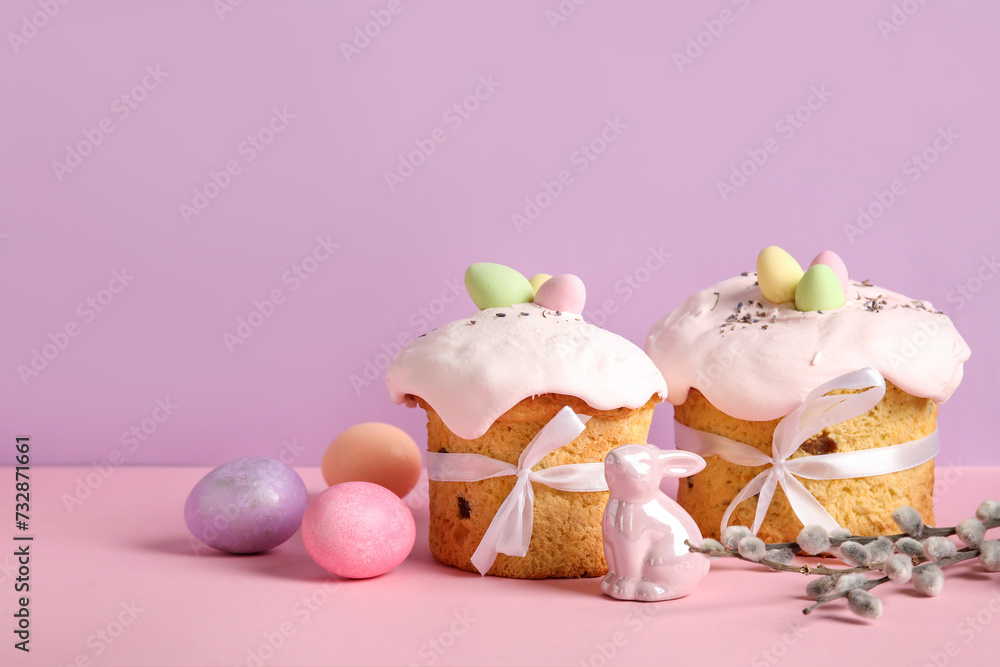 Composition with delicious Easter cakes, porcelain bunny and painted eggs on color background