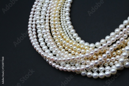 Expensive and luxurious Japanese saltwater Akoya pearls on strands of white, pink and golden organic gems ready to be made into necklaces and sold in jewelry store. photo