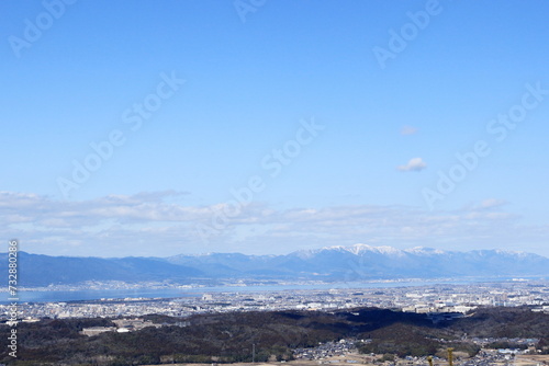 青空の下に広がる琵琶湖と湖西の雪山