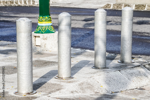 Metallic long inground bollard pole barrier between asphalt road and sidewalk to protect pedestrians and roadside decoration. Town square, urban, city, infrastructure. In Ground Metal Bolard. photo