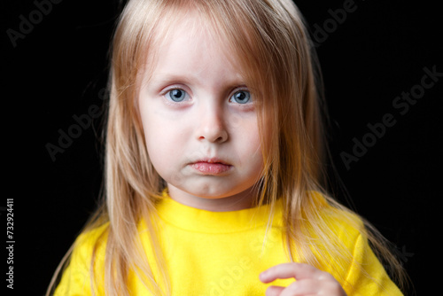 Emotional child. Little girl with big gray eyes is sad and looks at the camera.