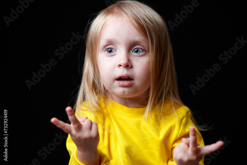 Emotional child. The girl is surprised by showing something on her fingers. Funny childish emotions.