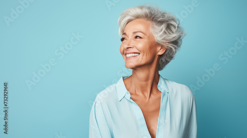 a carefree mature woman  striking a pose against a pastel blue backdrop