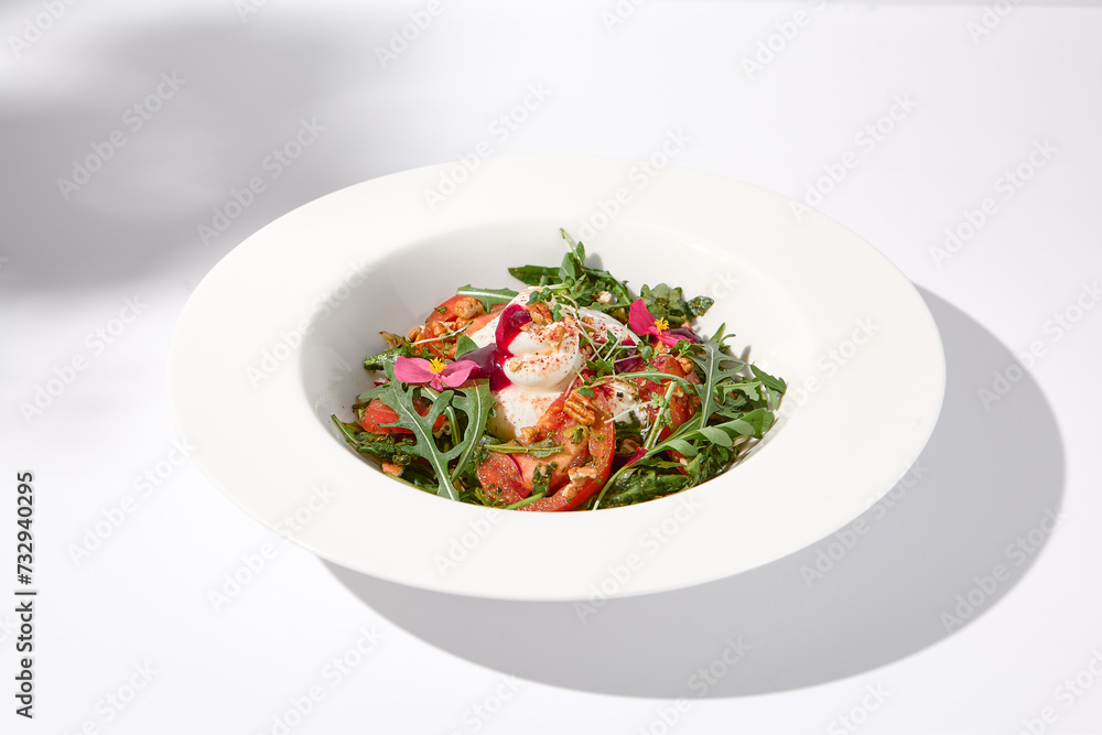 Italian salad with burrata, tomatoes, and arugula in shadow, garnished with edible flowers