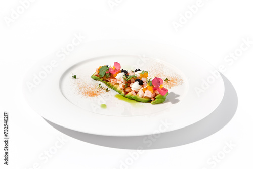 Gourmet avocado with shrimp tartare, mango, cream cheese, and black caviar on a pristine white plate