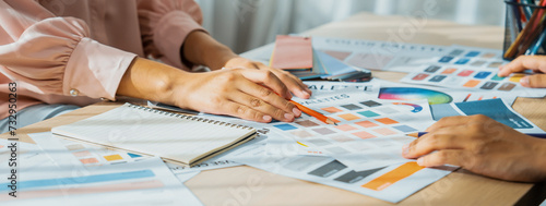 Cropped image of professional interior designers discuss and brainstorm main theme color in project on meeting table with color palette scatter around. Creative interior design concept. Variegated.