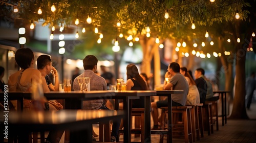 People enjoying music and beer at an outdoor street bar in Asia, bokeh effect photo