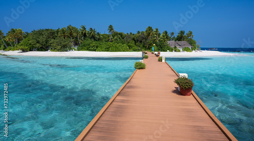 Wooden bridge over the sea leading to an island with sandy beaches and a green forest. Palm trees. © Denis
