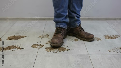 A man walks and stomps in dirty shoes on the ceramic floor. Boots in the mud. A man leaves dirt marks on the floor.