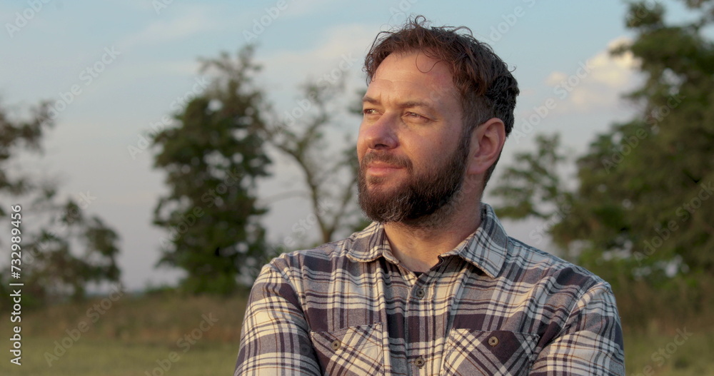 Portrait of a male farmer standing outdoors in a field. A man in a checkered shirt. Cheerful farmer crossing his arms. Agricultural business. Portrait of a male farmer standing outdoors in a field. A man in a checkered shirt. Cheerful farmer crossing his arms. Agricultural business.