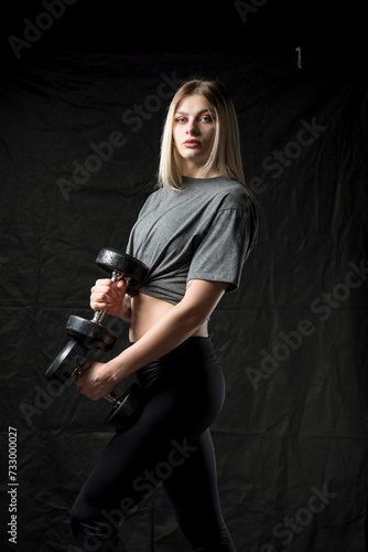 A beautiful young girl is working out in the gym in sportswear.