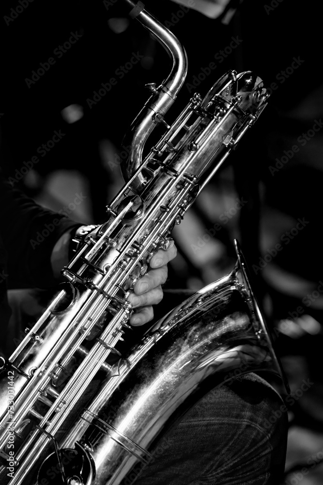 Obraz premium Baritone saxophone in the hands of a musician close-up in black and white