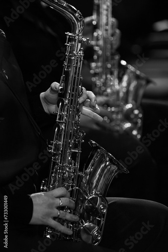 Hands of a girl playing the saxophone in an orchestra in black and white
