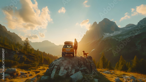 A man and woman have a road trip by a car with a dog. They look out at mountains. photo