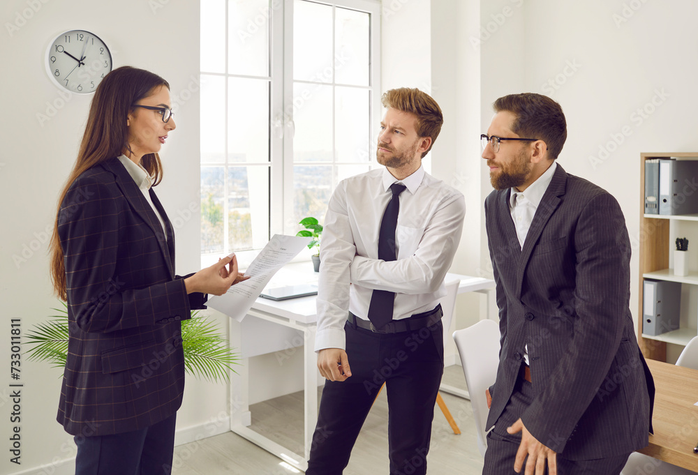 Portrait of three business people standing in office near the workplace discussing successful deal or signing contract. Coworkers talking with colleagues on a meeting considering new projects.