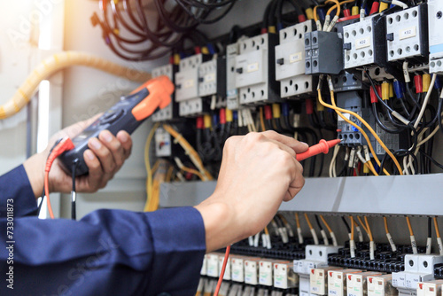 Electrician measurements with multimeter testing current electric in control panel.	 photo