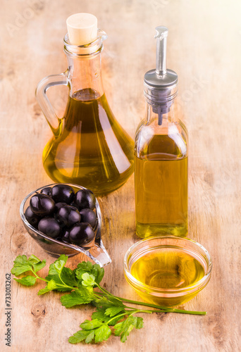 Olive oil with fresh herbs and Black olives on the wooden background