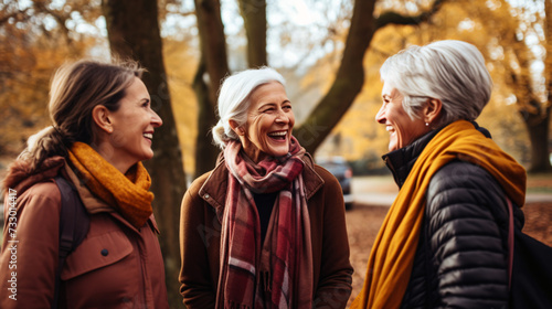 Cheerful senior women looking at each other while walking in autumn park