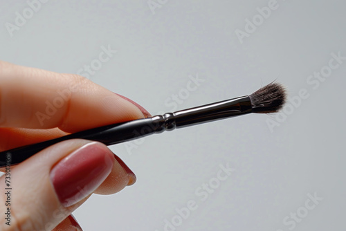 Hand holding make-up brush cosmetic isolated on gray