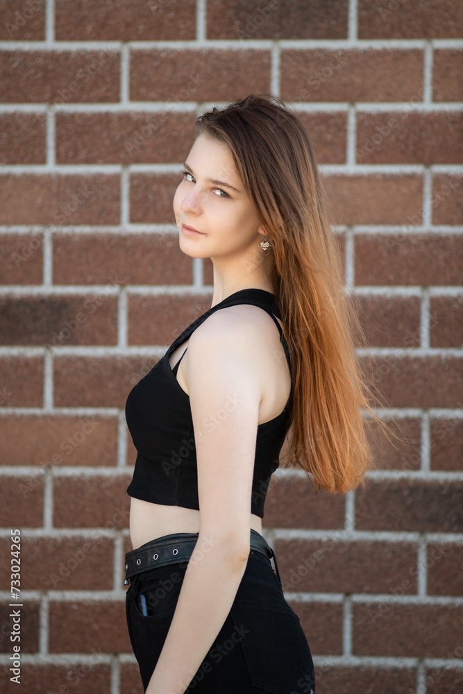 Portrait of a young beautiful long-haired girl in dark clothes on a summer street. Portrait of a young beautiful long-haired girl in dark clothes on a summer street.