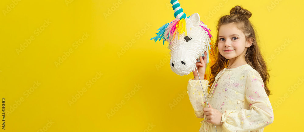 A little girl on a yellow background with a unicorn pinata. The banner. A little girl on a yellow background with a unicorn pinata. The banner.