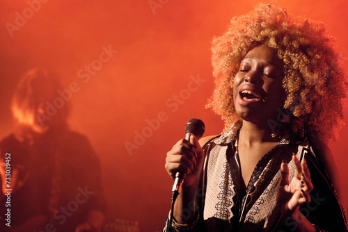 Obraz na plátně Waist up portrait of talented Black female musician singing to microphone during