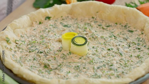 The chef prepares a pie with multi-colored zucchini and carrots, Tuscan pie, puts zucchini and carrot rolls on a cottage cheese crust, veganism, vegetables, home cooking. Side view, close-up, macro
