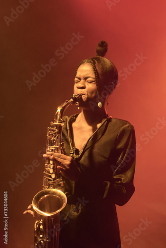 Sticker Vertical portrait of African American young woman playing saxophone while perfor