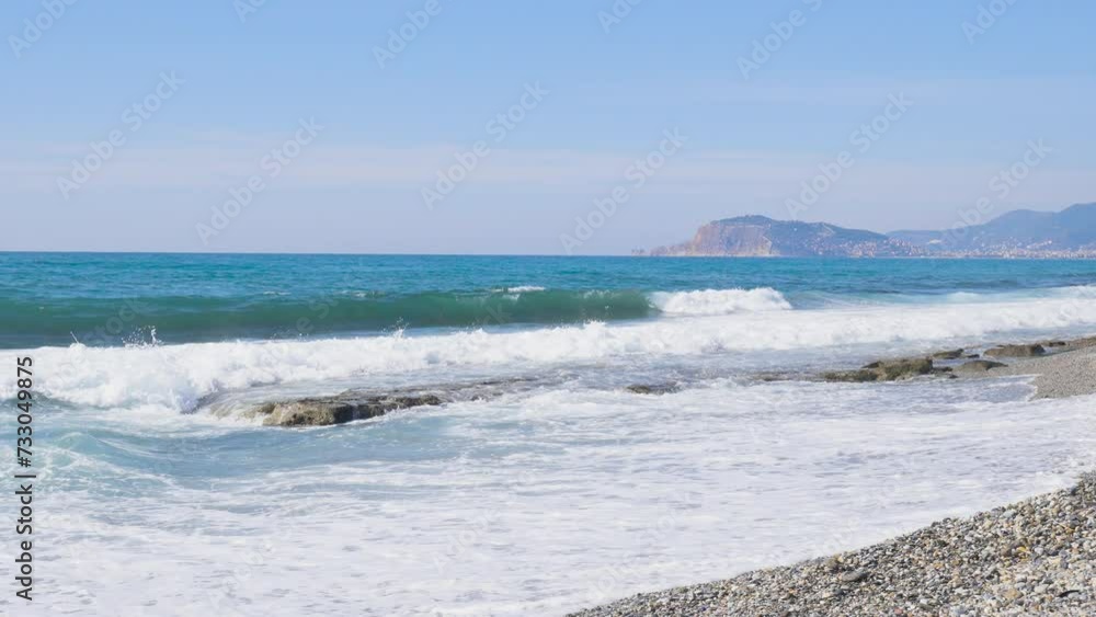Scenic Clean And Clear Turquoise Ocean Water Waves Crashing To The Idyllic Paradise Tropical Rocky Beach Shore on a sunny day during summer. Alanya beach Turkey with beautiful sky and clear water Scenic Clean And Clear Turquoise Ocean Water Waves Crashing To The Idyllic Paradise Tropical Rocky Beach Shore on a sunny day during summer. Alanya beach Turkey with beautiful sky and clear water