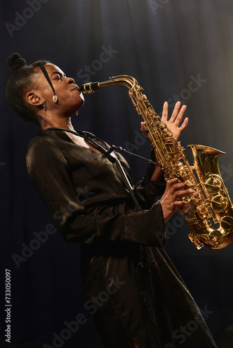 Photography Side view portrait of passionate African American woman playing saxophone on sta