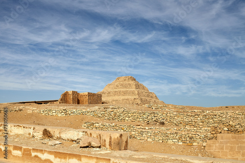 View of the step pyramid of Djoser together with some dummy buildings inside the complex, under dramatic blue sky - Saqqara, Egypt