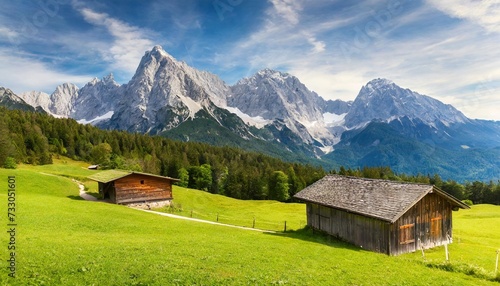 alpine green meadow and wooden barns zugspitze mount in the background garmisch partenkirchen bavaria germany