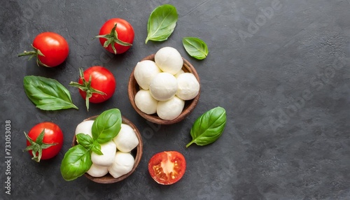 mozzarella cheese balls and slices with basil leaves and cherry tomato on a dark background top view flat lay copy space