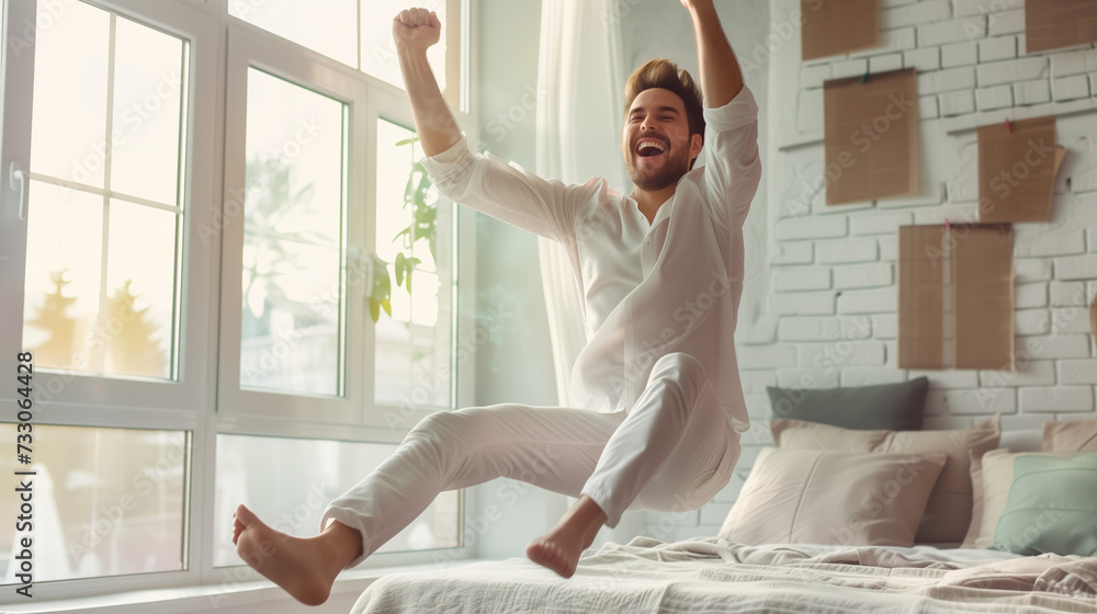 Joyful man leaps from bed with arms raised on a bright morning